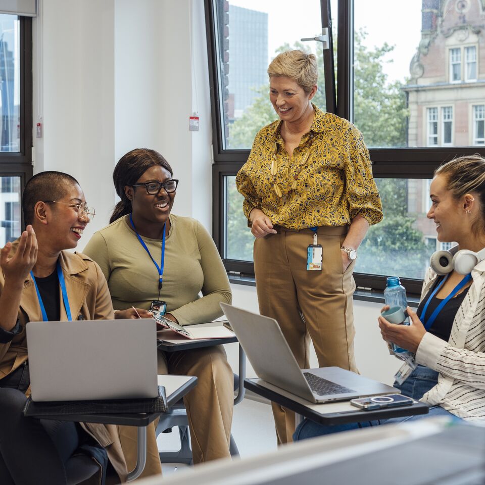 COLOUR-IMAGE_female-teacher-discussing-with-three-students_apr26