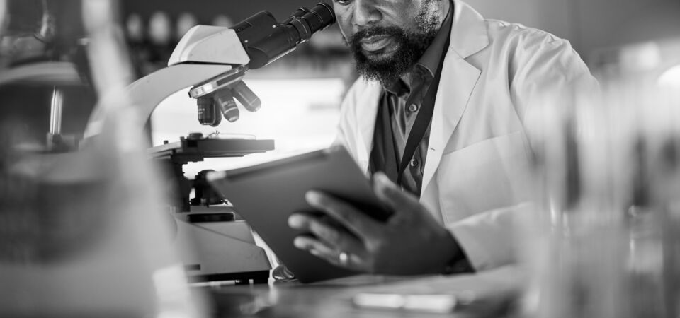 SINGLE-IMAGE_black-man-pharmacist-with-microscope_aug24