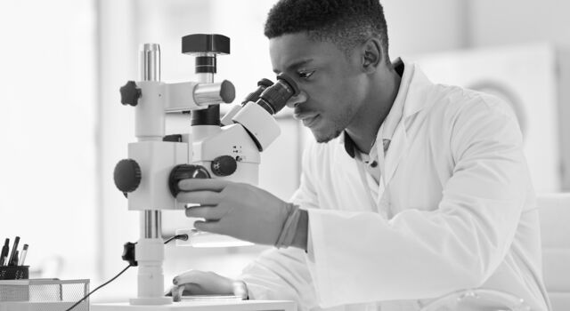 SINGLE-IMAGE_scientist-looking-at-test-samples-through-a-microscope_mar25